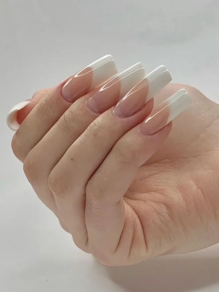 Classic French tip acrylic nails with glossy nude base